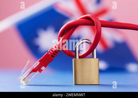 Ein geschlossenes Schloss auf einem gekoppelten Netzwerkkabel in einen Knoten vor dem Hintergrund der australischen Flagge, dem Konzept der Sicherheit von Internettechnologien in Au Stockfoto