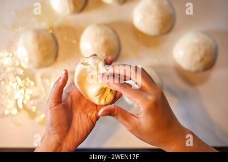Schließen Sie die Hände, die Teig für Pizza vorbereiten Stockfoto