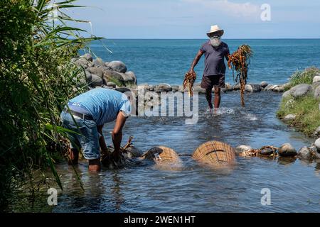 Zwei Fischer stehen in Riviere Saint Etienne, während sie mit einem traditionellen Vouve-Werkzeug Bichique-Fisch auf der Insel Réunion fangen. Stockfoto