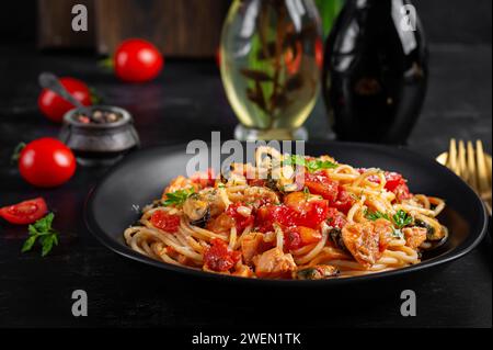 Klassische italienische Pasta Spaghetti Marinara mit Muscheln und Lachs auf dunklem Tisch. Spaghetti-Pasta mit Marinara-Sauce. Stockfoto