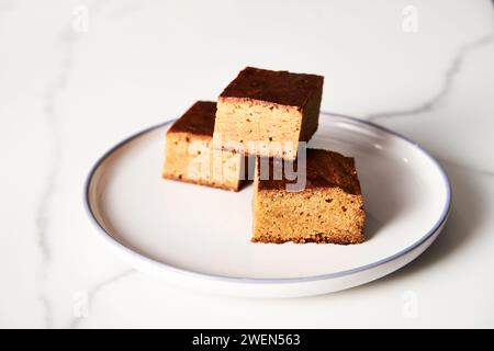 Süßes Frühstück. Blondies Bars auf weißem Teller, heller Hintergrund luftiges Mood Food Foto Stockfoto