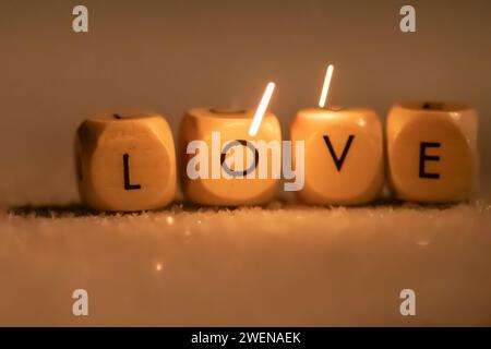 Hölzerne Würfel mit den Buchstaben LIEBEN auf einer mattierten Oberfläche mit einem Blitz von Licht auf das Wort Stockfoto