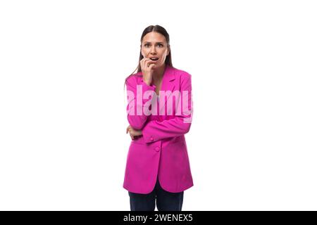 Die junge, gepflegte europäische Brünette mit schwarzen, glatten Haaren in einer stilvollen purpurroten Jacke macht sich Sorgen Stockfoto