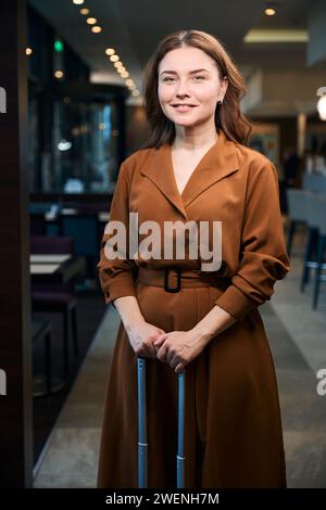 Eine stehende Frau hält einen Koffer Stockfoto