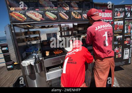 Zwei Männer in roten Uniformen arbeiten an einem Verkaufsstand von Hot Dog am Santa Monica Pier Stockfoto