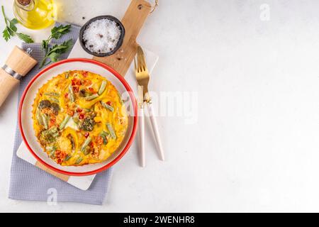 Hausgemachte Gemüseauflauf Frittata, gesunde vegetarische Speisen, Bratpfanne oder im Ofen gebackenes Eieromelette mit Gemüse auf weißem Marmor Küchentisch Co Stockfoto