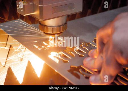 Metalllaserschneiden. Schneiden von Blechen durch Laserschneiden von Metall in Nahaufnahme. Maschinen für Industrieanlagen zum Schneiden von Metall im Werk. Beweglicher Kopf mit Funken. Hintergrund der Metallverarbeitung Stockfoto
