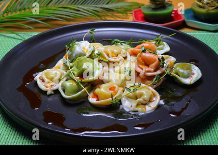 Italienische Tortellini Pasta in Sahnesauce.mit Spinat. Weißer Holzhintergrund. Draufsicht Stockfoto