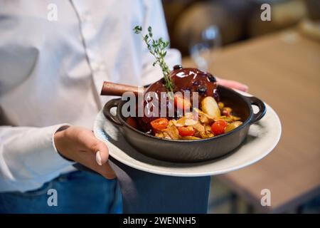 Die Kellnerin trägt eine im Ofen gekochte Lammkeule Stockfoto