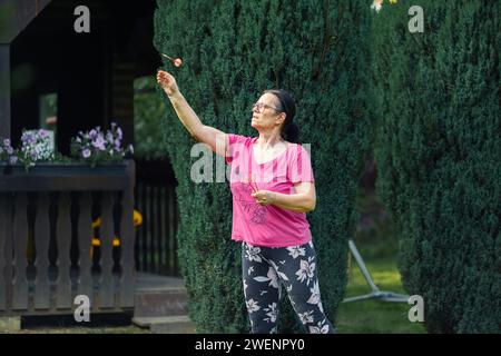 Eine ältere Frau, die im Garten Dart spielt. Sie ist an einem Sommertag im Freien Stockfoto