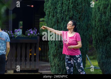 Eine ältere Frau, die im Garten Dart spielt. Sie ist an einem Sommertag im Freien Stockfoto