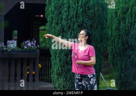 Eine ältere Frau, die im Garten Dart spielt. Sie ist an einem Sommertag im Freien Stockfoto