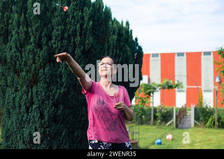 Eine ältere Frau, die im Garten Dart spielt. Sie ist an einem Sommertag im Freien Stockfoto