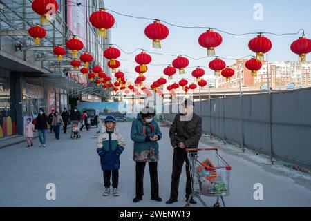 Die Verbraucher verlassen ein mit roten Laternen dekoriertes Einkaufszentrum nach dem Einkaufen, während das chinesische Frühlingsfest in Peking naht. 01-Jan-2024 Stockfoto