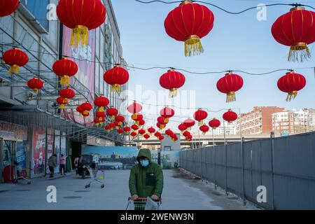 Die Verbraucher verlassen ein mit roten Laternen dekoriertes Einkaufszentrum nach dem Einkaufen, während das chinesische Frühlingsfest in Peking naht. 01-Jan-2024 Stockfoto