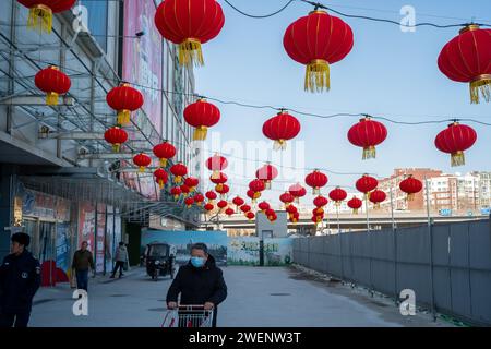 Die Verbraucher verlassen ein mit roten Laternen dekoriertes Einkaufszentrum nach dem Einkaufen, während das chinesische Frühlingsfest in Peking naht. 01-Jan-2024 Stockfoto