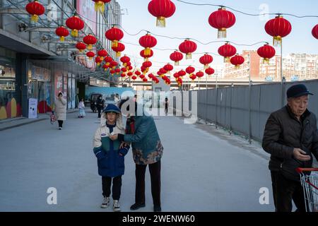 Die Verbraucher verlassen ein mit roten Laternen dekoriertes Einkaufszentrum nach dem Einkaufen, während das chinesische Frühlingsfest in Peking naht. 01-Jan-2024 Stockfoto