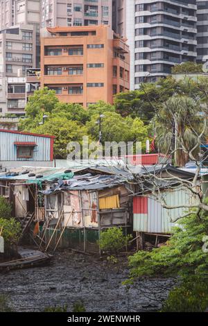 Beispiel für Gentrifizierung mit schlechtem Pfahlhaus im Schlamm im Kontrast zu modernen Hochhäusern im Tamsui District, Taipei, Taiwan. Stockfoto