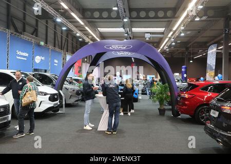 Erfurt, Deutschland. Januar 2024. Besucher stehen zwischen Autos in einer Ausstellungshalle der Automobil Messe Erfurt. Insgesamt 130 Aussteller zeigen in drei Messehallen die neuesten Entwicklungen im Automobilmarkt. Quelle: Bodo Schackow/dpa/Alamy Live News Stockfoto