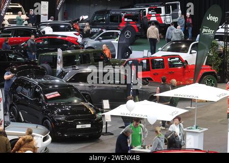 Erfurt, Deutschland. Januar 2024. Besucher stehen zwischen Autos in einer Ausstellungshalle der Automobil Messe Erfurt. Insgesamt 130 Aussteller zeigen in drei Messehallen die neuesten Entwicklungen im Automobilmarkt. Quelle: Bodo Schackow/dpa/Alamy Live News Stockfoto