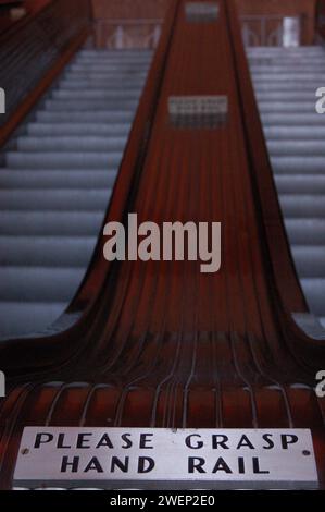 Ein Vintage-Art-Deco-Schild in der Nähe einer Rolltreppe erinnert die Leute daran, das Geländer auf der Rolltreppe im Rockefeller Center in New York City festzuhalten Stockfoto