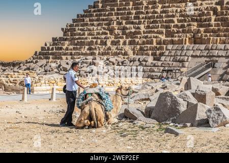 Gizeh Nekropolis, Ägypten - 26. April 2022: Ein Polizist der Touristenpolizei, sichtbar müde und von der Sonne erwärmt, ruht neben einem Kamel mit Wimpern Stockfoto