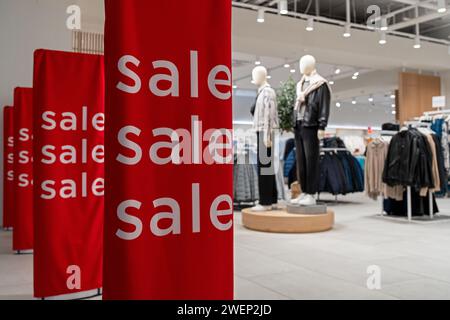 Verkaufsschild am Eingang zum Bekleidungsgeschäft - große rote Tafeln mit weißen Wörtern. Eine Reihe von VERKAUFSSCHILDERN in einem Bekleidungsgeschäft Stockfoto