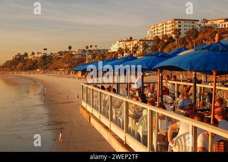 Gäste des Cafés genießen ihre Mahlzeit am Pier in San Clemente, Kalifornien, während die Sonne auf dem Meer untergeht Stockfoto