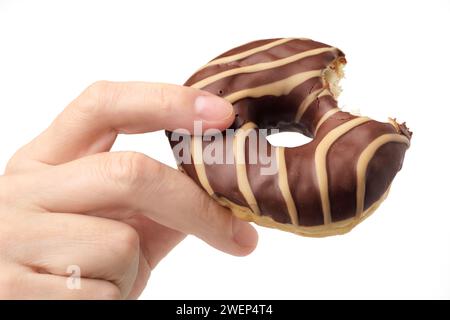 Menschliche Hand hält gebissene, gestreifte Schokolade und Karamell-Donut, isoliert auf weißem Hintergrund Stockfoto