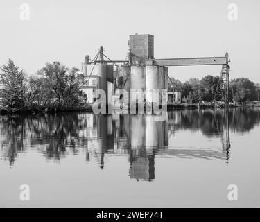 Blick aus der Vogelperspektive auf einen malerischen See mit einem markanten Getreideaufzug, umgeben von üppigen Bäumen Stockfoto