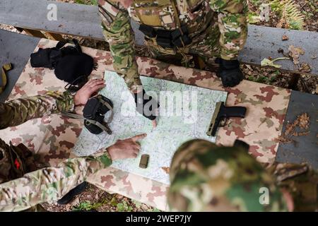 Eine gut ausgebildete Militäreinheit organisiert eine taktische Mission, während sie während einer Besprechung eine Militärkarte studiert Stockfoto