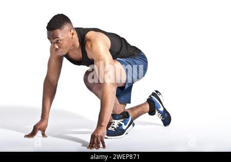 Ein junger schwarzer Brite im Sprint-Start. Stockfoto