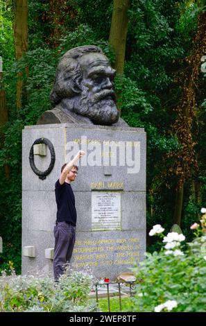 London: Am Grab von Karl Marx. - Ein junger Mann steht auf dem Highgate-Friedhof in London mit erhobener Faust neben der gepflegten Grabstätte von Kar Stockfoto