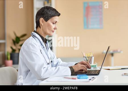Reife weibliche Gesundheit Praktikerin, die auf Laptop arbeitet Stockfoto
