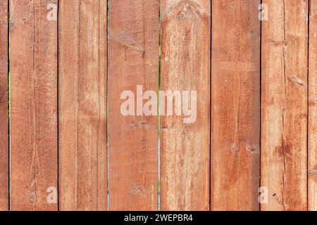 Fragment eines Zauns aus altem, unbeplanktem, in Reihen von Dielen angeordnet, rot bemalt. Als abstrakter Hintergrund und Textur zu verwenden. Stockfoto
