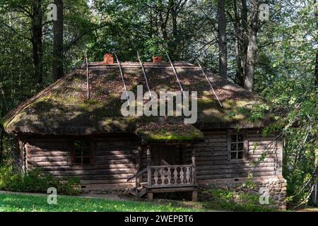 Altes Blockbadehaus mit Strohdach und Holzveranda steht auf einer Schräge im Wald, nicht weit vom Fluss entfernt. Stockfoto