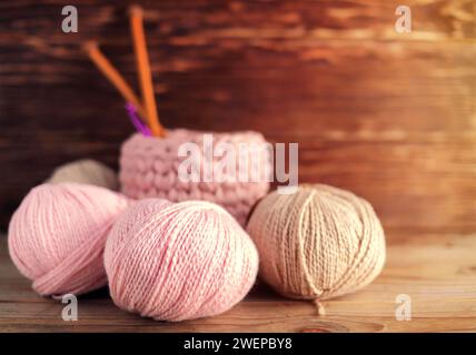 Kugeln aus Wollgarn und Holzstricknadeln auf hölzernem Hintergrund.Stricken. Eimer mit Strickzubehör. Stockfoto
