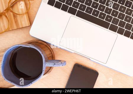 Becher neben dem Computer auf dem Schreibtisch Stockfoto