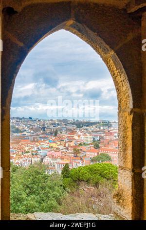 St. Georges Schloss in Lissabon, Portugal. Mittelalterliches Fenster in einem Turm, der das moderne Stadtbild umrahmt. Stockfoto