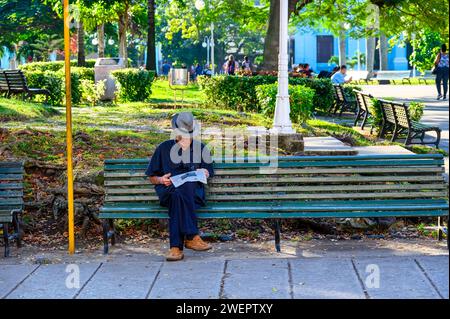 Senior-Mann liest Zeitung in der Parkbank, Santa Clara, Kuba Stockfoto