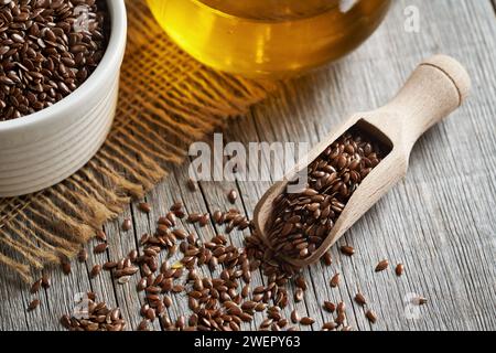 Leinsamen in einer Holzschaufel mit Leinsamenöl im Hintergrund Stockfoto