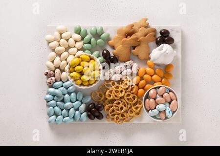 Ostersüße Wurstplatte mit Schokoladeneiern, süßen Süßigkeiten, Keksen als Häschen und Marshmallows auf weißem Hintergrund. Draufsicht. Festlicher Snack. Stockfoto