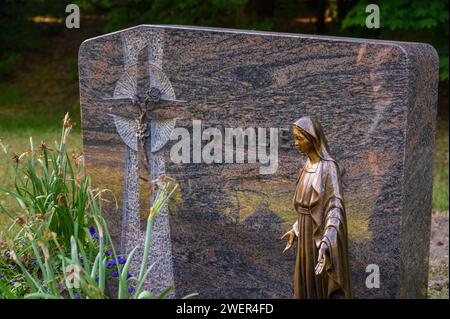 Grabstein mit einer Bronzestatue der Jungfrau Maria darauf Stockfoto