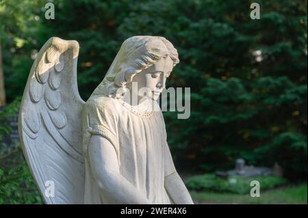 Engelsfigur am Grab vor grünem Hintergrund Stockfoto