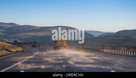 Streuwagen streuen Salz auf der Südseite der Autobahn M6 zwischen Shap und Tebay an einem kalten Winternachmittag in Cumbria, Großbritannien. Stockfoto