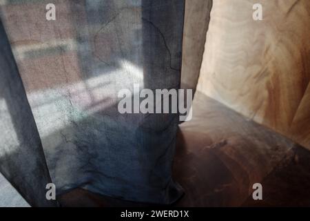 Eine Nahaufnahme der durchsichtigen, transparenten Vorhänge, die sanft auf einen polierten Hartholzboden treffen. Stockfoto