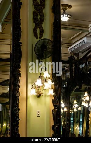 Blick auf die Inneneinrichtung mit goldenen Kronleuchtern und großen Kristallspiegeln an den Wänden des Hauptzimmers des Kaffeehauses Confeitaria Colombo. Stockfoto