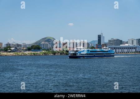 Corcovado CCR Fährschiff, das auf dem blauen Wasser der Guanabara Bucht fährt und den Bahnhof Arariboia im Bezirk Niteroi Centro unter dem blauen Himmel des Sommernachmittags verlässt. Stockfoto