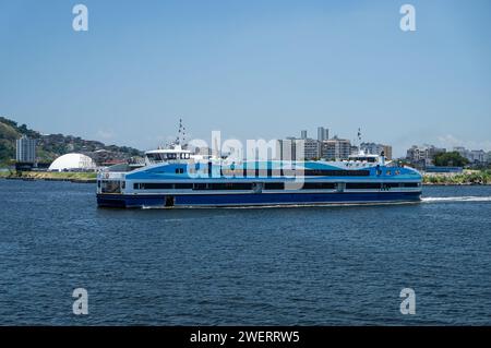 Corcovado CCR Fährschiff, das auf den Gewässern der Guanabara Bucht fährt und den Bahnhof Arariboia im Stadtteil Centro von Niteroi unter dem blauen Himmel am Sommernachmittag verlässt. Stockfoto