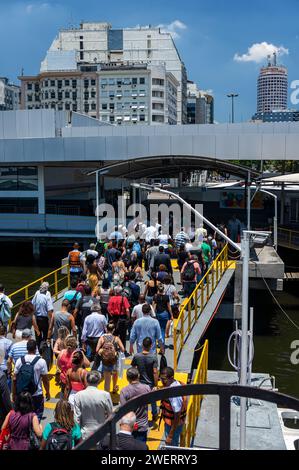 Passagiere, die die Fähre verlassen, die gerade am Bahnhof Arariboia angekommen ist, kommen aus Rio de Janeiro unter dem sonnigen, klaren blauen Himmel am Sommernachmittag. Stockfoto